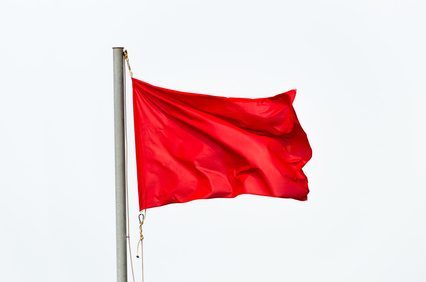 Red flag waving on the wind isolated over white.